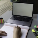 Profissional organizando anotações e planejamento ao lado de notebook para acompanhar propostas de orçamento