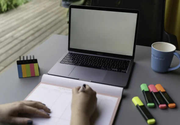 Profissional organizando anotações e planejamento ao lado de notebook para acompanhar propostas de orçamento
