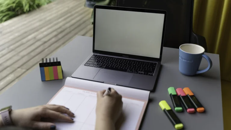 Profissional organizando anotações e planejamento ao lado de notebook para acompanhar propostas de orçamento